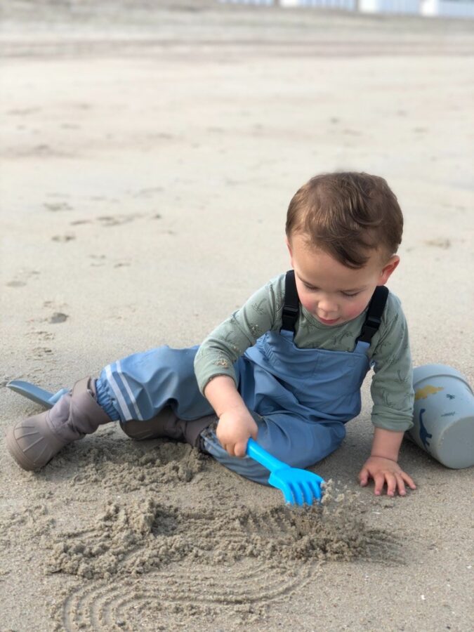 Jongen speelt in het zand op het strand met emmer en hark moddermonstertje.nl webshop kinderen