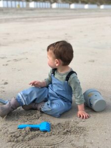 Kind speelt op het strand met emmer en harkje moddermonstertje webshop kinderen - ontwikkeling kind door buitenspelen
